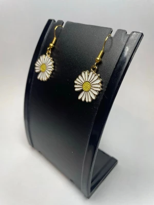 Hängande örhängen med prästkrage - Säljer ett par söta örhängen med prästkrage-design. Blommorna är vita med gul mitt och har guldfärgade krokar. Perfekta för dig som gillar blommiga accessoarer och vill ha en lekfull touch till din stil.