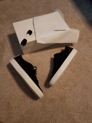 Common Projects  Achilles Low Suede - Säljer ett par Common Projects Achilles Low Suede Black i storlek 44. Skorna är tillverkade i Italien med högst kvalité av läder och mocka. Skorna följer med allt som är på bilderna dvs box,extra skosnören och dustbag. Slutsålda i princip överallt nypris 3500-4500kr.