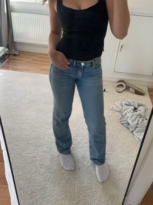 Blå raka jeans från ginatricot - Säljer ett par klassiska blå raka jeans från ginatricot. Jeansen har låg midja, silverfärgade knappar. Jag säljer jeansen på 2&3 bilden men första bilden är ej samma jeans, jeansen på första är likadana fast något ljusare men samma passform😊