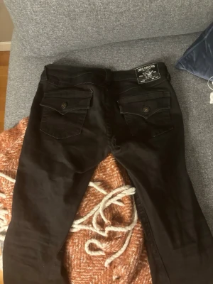 Svarta true religon jeans i modellen ”joey” - Säljer ett par svarta jeans från true religion i modellen joey. Dom är i storlek 27/32 men är ganska stretchiga. Bra skick, säljer för att dom är för stora. 