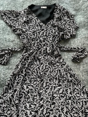 Svart blommig klänning  - En fin svart klänning med vitt blommönster och knytband🩷