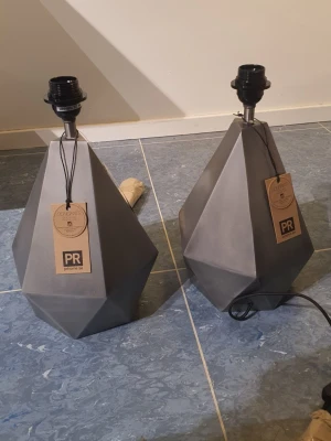 PR Home Trinity bordslampa grå - Säljer en PR Home Trinity bordslampa i matt grå metall med en unik, diamantformad design. Lampfoten är 39 cm hög och har en modern, grafisk look som passar perfekt som inredningsdetalj. 2 stycken. Nypris är ca 1400 kr st.