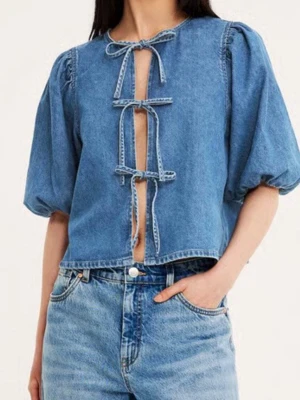 Blå jeansblus med puffärm och knyt - Trendig blå jeansblus med puffiga korta ärmar och öppen front med flera knytband. Tillverkad i denim för en cool och avslappnad look. 