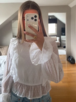 Vit volangblus från NA-KD - Säljer en vit blus från NA-KD med volanger och prickigt transparent tyg. Blusen har långa ärmar och är i storlek xs🤍