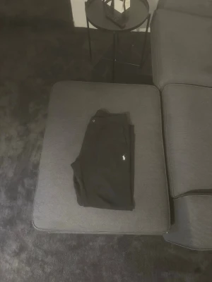 Svarta mjukisbyxor från Ralph Lauren - Säljer ett par svarta mjukisbyxor från Ralph Lauren med den klassiska vita loggan broderad på benet. Byxorna har en avslappnad passform och är perfekta för chill dagar. Tillverkade i mjukt material för extra komfort.