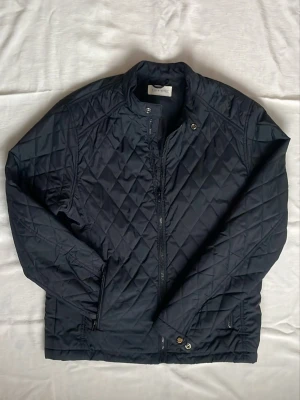 Svart quiltad jacka från Pier one - Snygg svart quiltad jacka från Pier one med dragkedja och tryckknappar vid halsen. Jackan har lång ärm, diskret ståkrage och två fickor med dragkedja. Perfekt för dig som gillar stilren och enkel design. Perfekt till våren och höst. Hör av dig vid frågor⁉️strl L