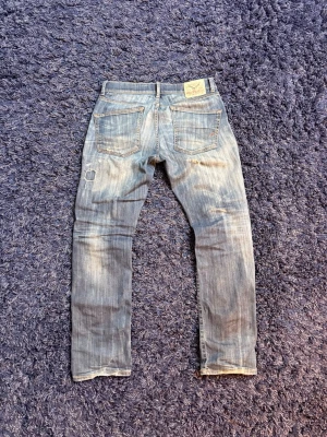 Ljusblå Hilfiger Denim jeans - Säljer ett par ljusblå jeans från Hilfiger Denim med raka ben och klassisk femficksmodell. Jeansen har slitningar och en liten patchdetalj på vänster ben. Tillverkade i bomull med en avslappnad vibe och tydliga tvätteffekter. De är galen passform och mycket skön tvätt och fades med få slitningar. Hör av er vid minsta fundering! W31 L32