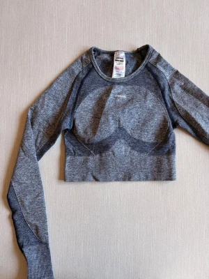 Gymshark top - En blå långärmad top från Gymshark som inte kommer till användning. Den har hål för tummar och i ryggen. Passar även XS.