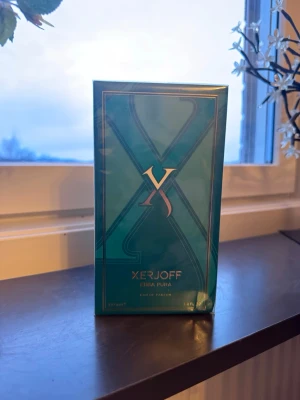 Xerjoff Erba Pura Eau de Parfum - Lyxig parfym från Xerjoff, Erba Pura, i en elegant turkosgrön förpackning med guldiga detaljer. Eau de Parfum, 100 ml. Känd för sin fräscha och fruktiga doftprofil och exklusiva känsla. Perfekt för dig som gillar unika och sofistikerade dofter.