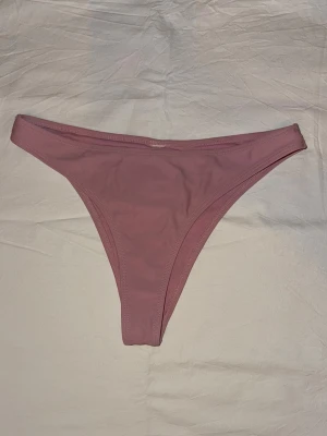 Bikinitrosa  - En stilren rosa bikiniunderdel. Perfekt för strandhäng eller poolparty. Materialet känns mjukt och följsamt mot huden. Ingen synlig logga eller mönster, bara clean och snygg look. Saknar lapp men skulle säga att den passar S/M/ 36/38