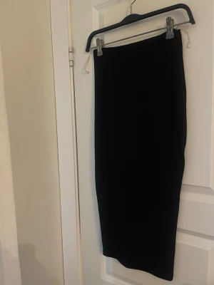 Nookie svart pennkjol - Nookie svart pennkjol – elegant & tidlös  Stilren svart pennkjol från exklusiva märket Nookie. En klassisk och feminin modell som sitter smickrande och ger en elegant silhuett. Perfekt både till fest, middag eller en mer dressad vardagslook.  Kjolen har en minimalistisk design med hög kvalitet i tyget som gör att den faller väldigt fint och håller formen. En riktig garderobsklassiker som aldrig går ur stil.  • Märke: Nookie • Färg: Svart • Storlek: 8 (motsvarar ca XS/S) • Modell: Pennkjol / midi