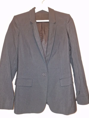 Svart kavaj från Acne Studios - Stilren klassisk kavaj, vilket ger en snygg och tidlös look. Perfekt för dig som vill ha en clean och dressad stil. Dyr i inköp och i väldigt fint skick 🖤