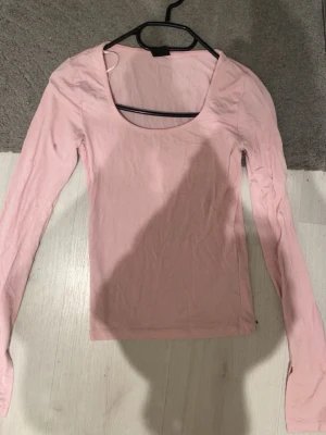 Ljusrosa långärmad topp - Söt ljusrosa basic långärmad topp med rundad, djup urringning. Perfekt att styla med jeans eller kjol för en enkel look!