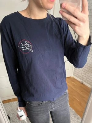 Mörkblå långärmad topp Jack & Jones - Mörkblå långärmad topp från Jack & Jones Originals med rund halsringning och tryck på bröstet. Tillverkad i mjuk bomull.