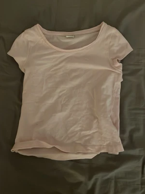 Ljusrosa kortärmad topp - En basic ljusrosa topp med rund halsringning och korta ärmar. Perfekt att matcha med jeans eller kjol för en enkel och fräsch look. I barn stolek! Är 128 alltså 7-8 men kan också passa i 10-11 åldern (beror självklart på)
