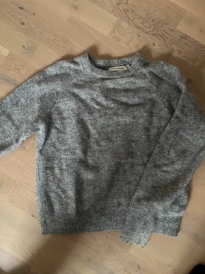 Grå stickad tröja  - Mysig grå stickad tröja från Carin Wester. Tröjan har en avslappnad passform.