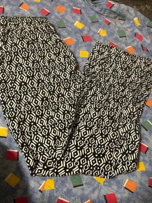Svarta och vita mönstrade leggings - Snygga leggings med svartvitt geometriskt mönster. De har en elastisk midja och är tillverkade i ett stretchigt material som sitter skönt på kroppen. Perfekta för dig som gillar att sticka ut med coola mönster och vill ha något bekvämt till vardags.