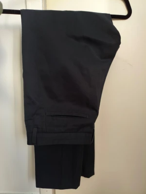 Hugo Boss Chinos  - Klassiska marinblåa chinos byxor med raka ben och diskreta bakfickor. Byxorna har en stilren passform och är sydda i ett mjukt, följsamt tyg som ger en clean look. Perfekta för dig som gillar enkel och tidlös stil.