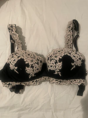 Svart spets-bh med beige brodyr Balconettebehå Sofia Pretty Flowers  - Snygg svart bh med vadderade kupor och dekorativ beige spetsbrodyr över kuporna och axelbanden. Justerbara axelband och hakknäppning bak. Perfekt för dig som gillar romantiska detaljer och stilren design.