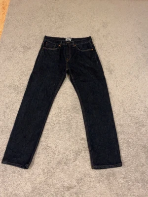 Mörkblå raka jeans - Snygga mörkblå jeans med rak passform och klassiska fem fickor. Jeansen har kontrastsömmar och knappgylf. Perfekta för en stilren och enkel look. Materialet är kraftig denim i bomull.