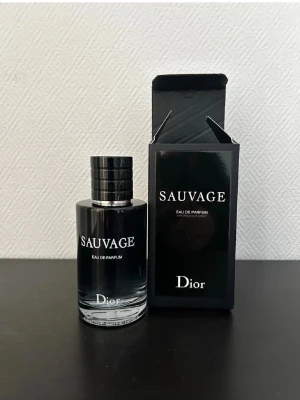 Dior Sauvage Eau de Parfum - Dior Sauvage Eau de Parfum med elegant svart glasflaska och matchande svart kartong. Flaskan har en stilren, rund form och tydlig logga framtill. En ikonisk doft som utstrålar lyx och modernitet.