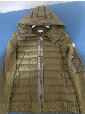 Olivgrön jacka från Moncler - Säljer denna unika snygga olivgrön jacka från Moncler med stickade ärmar. Tror ej den är äkta. Den är i jätte bra skick. Bra pris köp nu