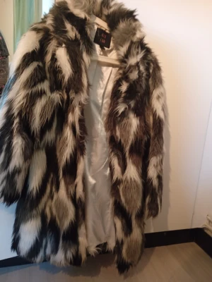 Fuskpälsjacka - Snygg och trendig fuskpälsjacka i svart, vitt och brunt. Jackan har ett fluffigt och lyxigt utseende med längre pälsimitation och helfodrad, sammets insida. Perfekt för dig som vill sticka ut och hålla dig varm under kalla dagar.