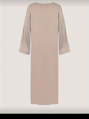Beige långklänning med vida ärmar - En stilren beige långklänning med raka linjer och vida långärmar. Klänningen har en minimalistisk design utan synliga detaljer och är perfekt för dig som gillar enkel och elegant stil. 