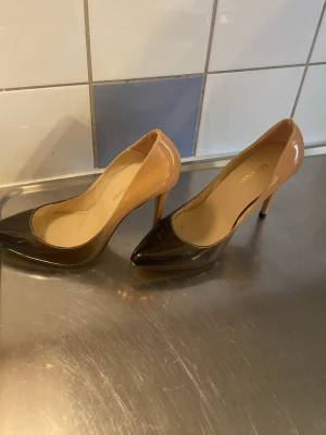 Bruna lackpumps från Losen Andipien - Snygga pumps i brunt och beige från Losen Andipien. Skorna har spetsig tå, hög klack och är tillverkade i glansigt lackmaterial. Perfekta för dig som vill ha en elegant och trendig look.