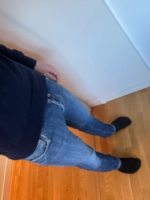 Blå slim fit jeans från Jacob Cohën - Snygga blå jeans från Jacob Cohën i slim fit-modell. Jeansen har klassisk femficksdesign, tydliga slitningar och kontrastsömmar. Tillverkade i stretchigt denim för en bekväm passform. Perfekta för en trendig och avslappnad stil. Råka köpa fel storlek därför säljer jag dom, knappt använda. Hör av er vid frågor!