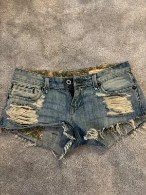 Blå slitna jeansshorts med fransar - Jag säljer ett par blå jeans shorts med slitningar💕 Säljer pågrund av försmå tyvärr. Dom är riktigt lågmidjade och korta. Använt flitigt. Men ingen fläck eller hål som förstört dom. Passar perfekt för en sommar luck💐💐 pris kan diskuteras!!