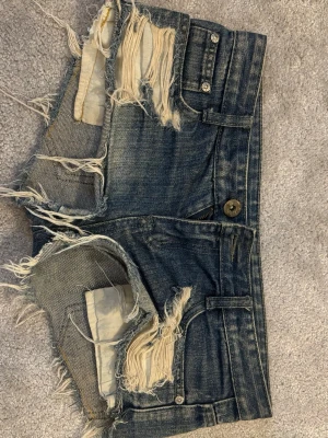 Blå slitna jeansshorts med fransar - Säljer blåa jeans shorts med slitningar. Dom är lågmidjade och korta i modellen. Säljer dom för att de är små tyvärr.  Små i storlek! Jätte fina till sommarn💕💐 Väldigt bra skick! Pris kan diskuteras 