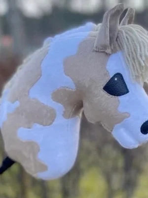 Käpphäst beige och vit - Säljer en käpphäst med mjuk plysch i beige och vitt, svart broderad nos och ögon samt ljust garnman. Perfekt för lek och fantasi, lätt att hålla i tack vare käppen.