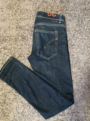 Dondup Jeans - Snygga mörkblå slim fit jeans från märket 96. Jeansen har klassisk femficksdesign, kontrastsömmar och en cool detalj med orange logga i midjan. Tillverkade i slitstarkt denim med lätt tvättade effekter för en trendig look.