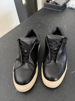 Svarta sneakers med lila detalj - Stilrena svarta sneakers i läder från eytys.