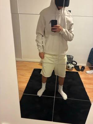 Vita shorts från Nike - Säljer ett par stilrena vita shorts från Nike med elastisk midja och diskret logga på vänster ben. Shortsen har en avslappnad passform och är tillverkade i ett mjukt, lätt material som passar perfekt till sommaren.