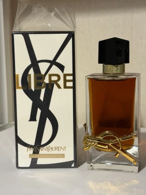 Yves Saint Laurent Libre EdP Intense 90ml - Yves Saint Laurent Libre Eau de Parfum Intense i 90 ml flaska. Parfymen kommer i en elegant, rektangulär glasflaska med guldiga detaljer och svart lock. Förpackningen är vit med stora svarta bokstäver och guldtext. En lyxig och modern doft för dig som vill sticka ut.