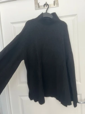 Svart polotröja stickad - Mysig svart stickad polotröja från Lager157 i storlek M. Tröjan har hög polokrage, lång ärm och är tillverkad i ett mjukt, tjockt material som passar perfekt när det är kallt ute. Enkel och stilren design som är lätt att matcha.