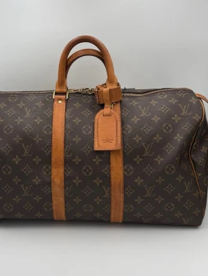 Louis Vuitton Keepall väska - Tidlös investering. Lyxig second hand LOUIS VUITTON KEEPALL 45 Monogram väska. Mångsidig och slitstark väska som erbjuder ikonisk stil och premiumkvalitet. En av de delar som skrev Louis Vuittons historia. Rymlig, slitstark och med visst värde. Redo för dig