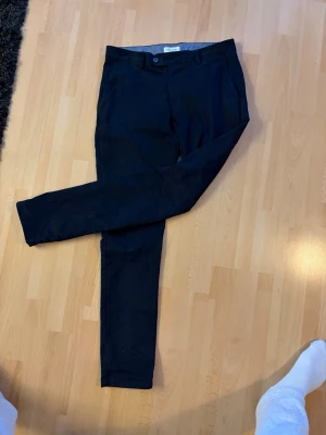 John Henric Chinos slim fit - Snygga mörkblå chinos med slim fit passform och klassisk design. Byxorna har två sidofickor fram och två bakfickor med knapp. Perfekta för en stilren look och passar till många olika outfits. W32 L32 men sitter mer som W31. 