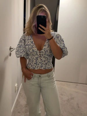 Blommig croppad blus med puffärm - Söt croppad blus med blått blommönster från HM. Blusen har puffiga korta ärmar, v-ringning och knappar framtill. Perfekt för sommarens alla tillfällen och ger en fräsch och trendig look💕💕