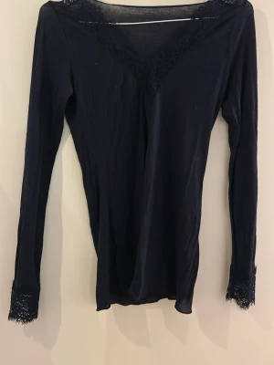 Mörkblå långärmad topp med spetsdetaljer - Mörkblå Intimissimi tröja i storlek S, har två små hål som är igensydda.