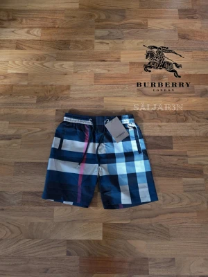 Rutiga shorts från Burberry - 🩳 Burberry Shorts – Storlek M 🩳 Stilrena Burberry shorts med klassiskt rutmönster, perfekta för sommar, strand eller avslappnad vardag. Elastisk midja med justerbar dragsko ger bekväm passform. Tillverkade i lätt och slitstarkt material med mjuk känsla mot huden. Praktiska fickor för småsaker och Burberry-logga. Liten markering på baksidan. Shortsarna är i nyskick. 📦 Snabb leverans (om ej hinder) – Kontakta för frågor!