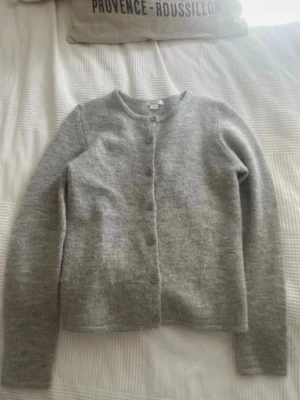Ljusgrå kofta från Gina Tricot - Mysig ljusgrå kofta från Gina Tricot med rund halsringning och knappar framtill. Tillverkad i ett mjukt, stickat material som passar perfekt för lager på lager. Enkel och stilren design som är lätt att matcha med olika outfits.