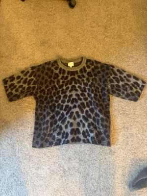 Grå leopardmönstrad stickad tröja - grå stickad tröja från H&M med leopardmönster i svart. Den är lagom tjockt i matrialet, men väldigt skön. Lite oversized också.