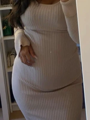 Beige ribbad långklänning - Säljer en beige ribbad långklänning med lång ärm och rund halsringning. Klänningen har en kroppsnära passform och är tillverkad i ett mjukt, stretchigt material som ger en snygg siluett. Perfekt för dig som gillar stilrena och enkla plagg.
