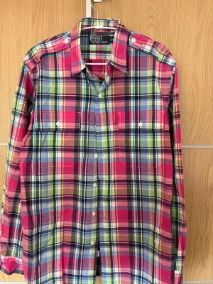 Rutig skjorta från Polo Ralph Lauren - Färgglad rutig skjorta från Polo Ralph Lauren i bomull. Skjortan har långa ärmar, klassisk krage och knäppning framtill samt två bröstfickor med knapp. Perfekt för dig som gillar en färgstark och avslappnad stil.