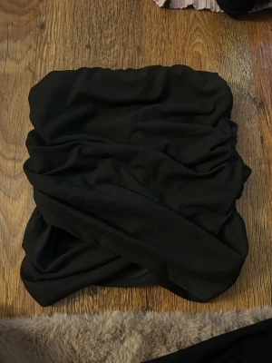 Svart kortkjol från SHEIN - En svart kortkjol från SHEIN i stretchigt material med snygga rynkade detaljer. Kjolen är enkel och stilren, perfekt att matcha med olika toppar för en trendig look. Tillverkad i polyester och elastan för skön passform.