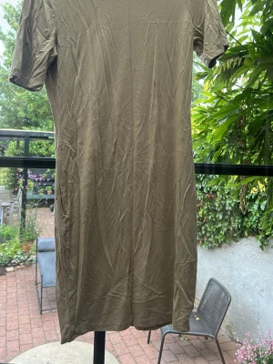 Beige kortklänning från NA-KD - En enkel och stilren grön kortklänning från NA-KD. Klänningen har rund halsringning och korta ärmar. Tillverkad i mjukt material som känns skönt mot huden. Perfekt för en avslappnad och trendig look.