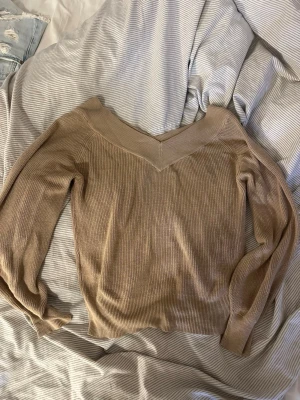 Beige stickad tröja Vero Moda - Säljer en beige stickad tröja från Vero Moda med v-ringad hals och långa ärmar. Tröjan har en ribbad struktur och är perfekt för dig som gillar en enkel men snygg stil. Passar till allt och är superbekväm.